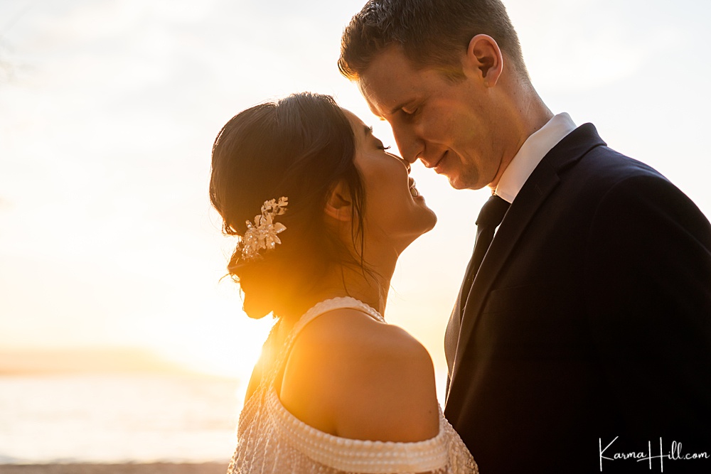 bride and groom kissing in front of the sunset on Maui 