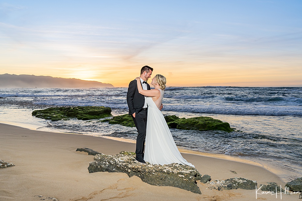 bride and groom embracing for wedding photos on oahu with the sunset 