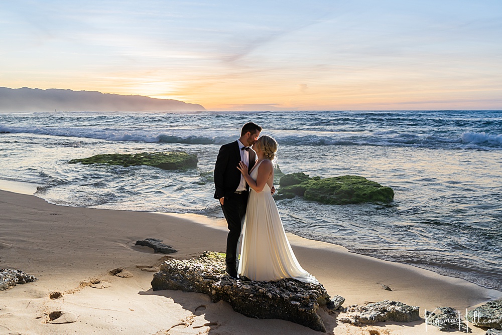 bride and groom kissing on Oahu beach during sunset 