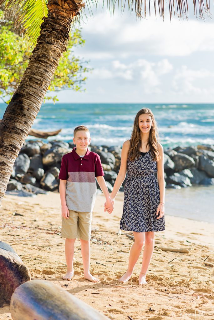 brother and sister holding hands on Kauai beach 
