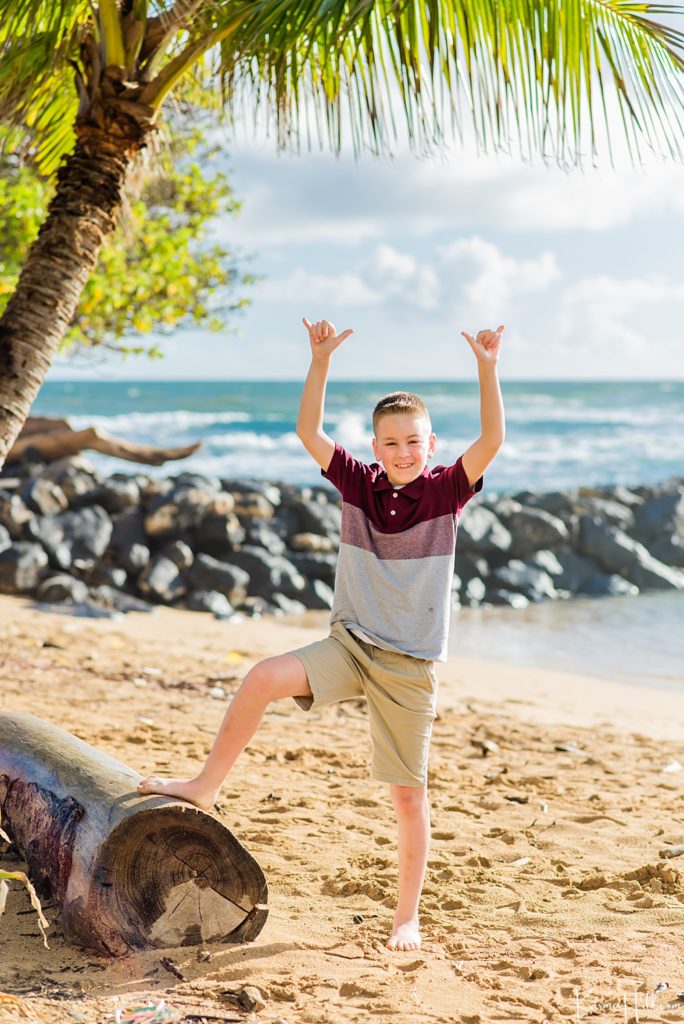 Happy young boy giving shaka on a Kauai beach 