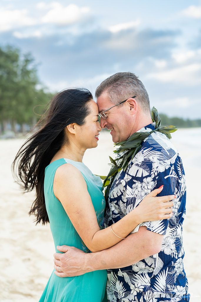 Oahu couple's portrait - woman and man touching foreheads while embracing on the beach 