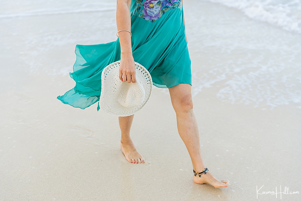 closeup of a woman's legs in a teal dress as she walks on the beach 