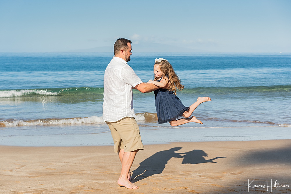 Man on the beach lifting his daughter into the air