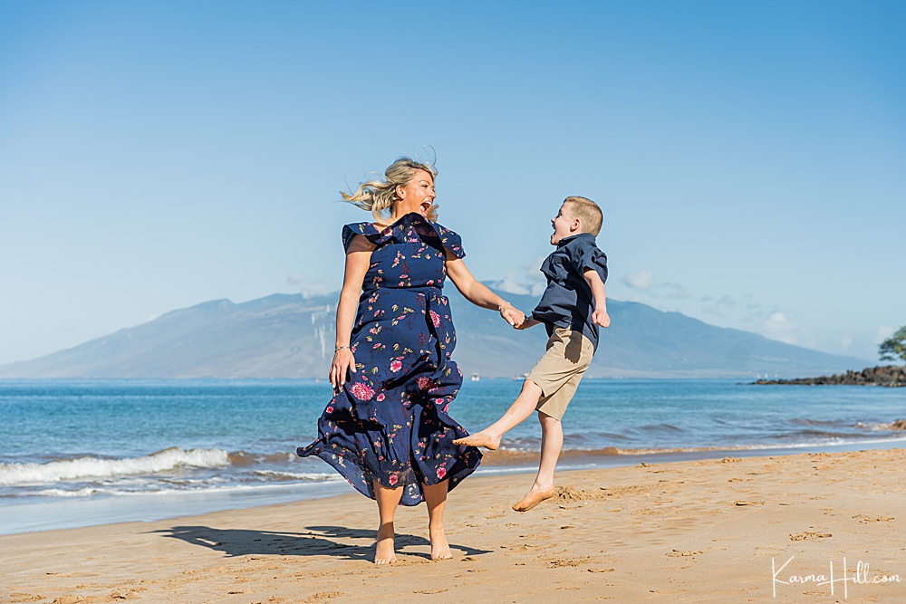 Woman and young son jumping and laughing on the beach 