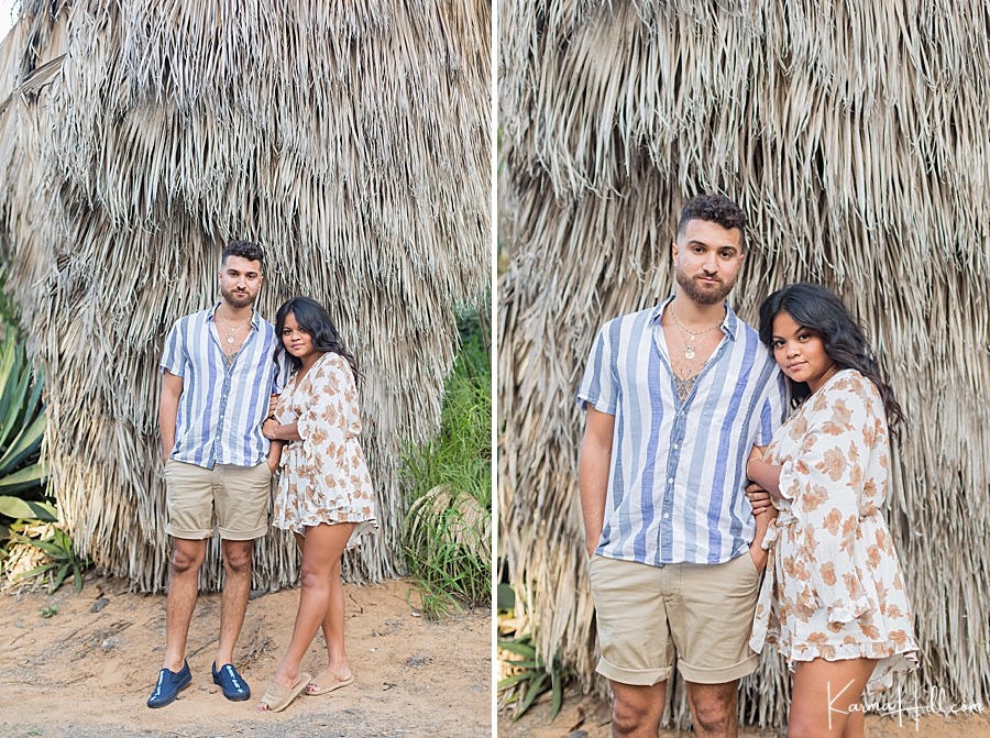couple standing in front of hawaiian style hut 