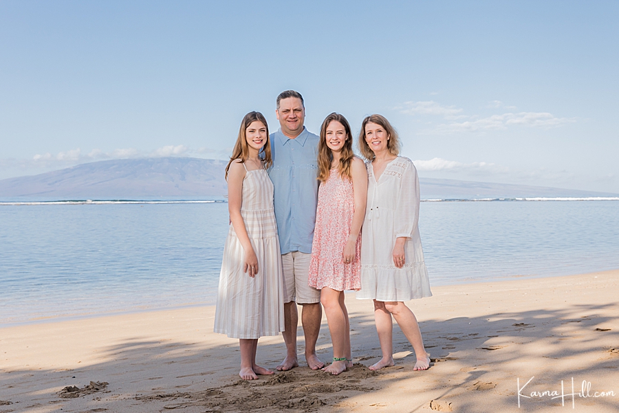 family poses in pastel colors in beach on Maui 
