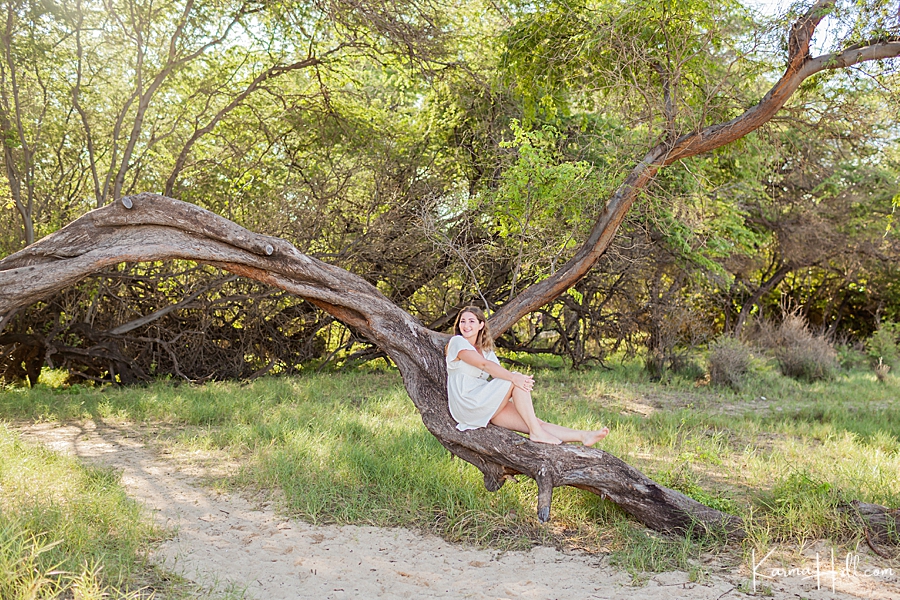 young woman sitting on a kiawi tree in hawaii 