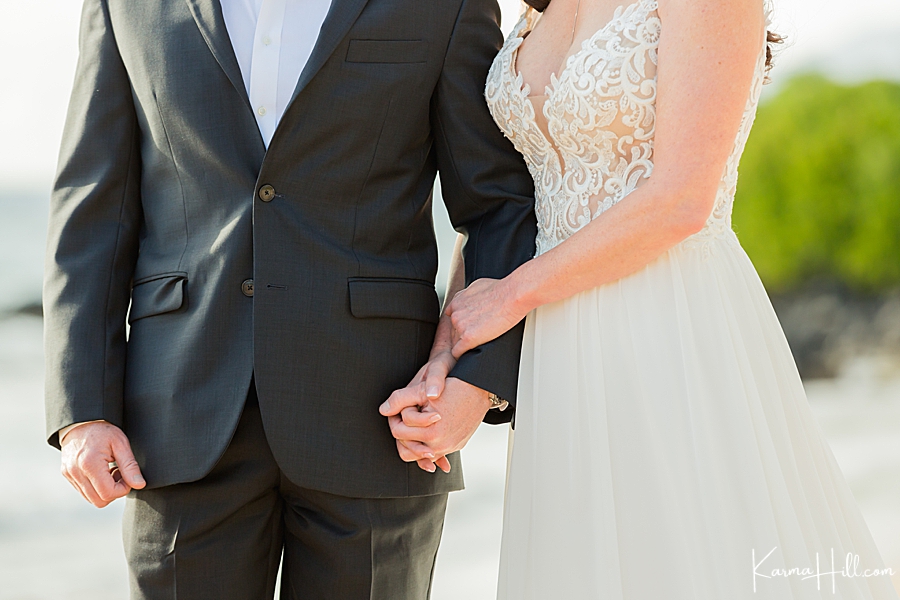 close up of bride and groom holding hands during wedding in hawaii 