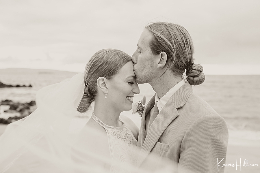 black and white image of bride and groom kissing on maui beach 