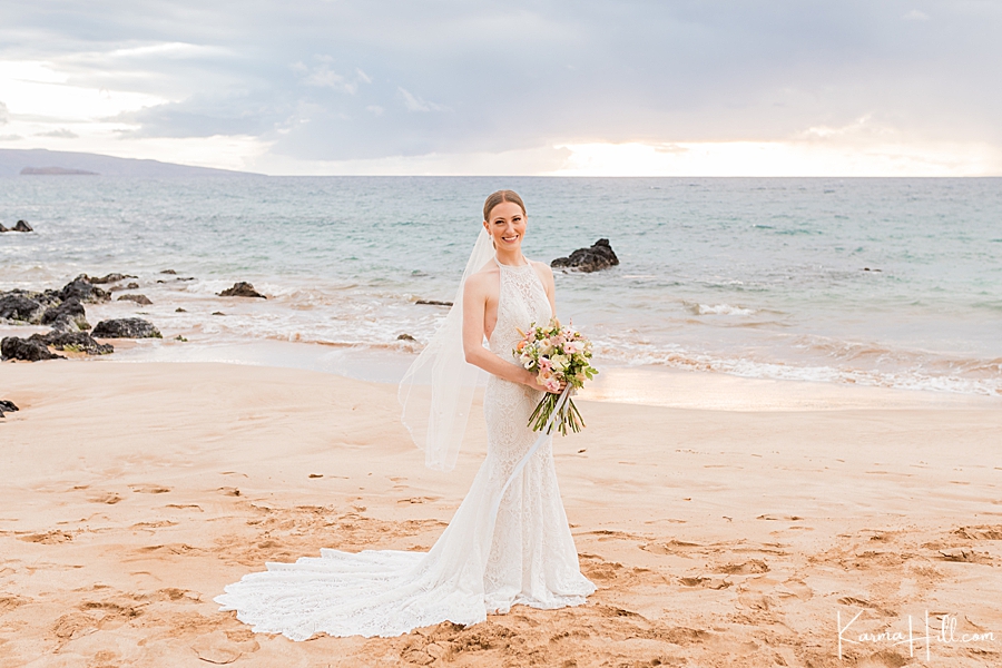 bride in a halter boho dress with long trail on hawaii beach 