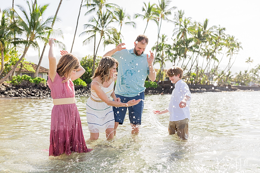 family of four splash in the ocean on maui 