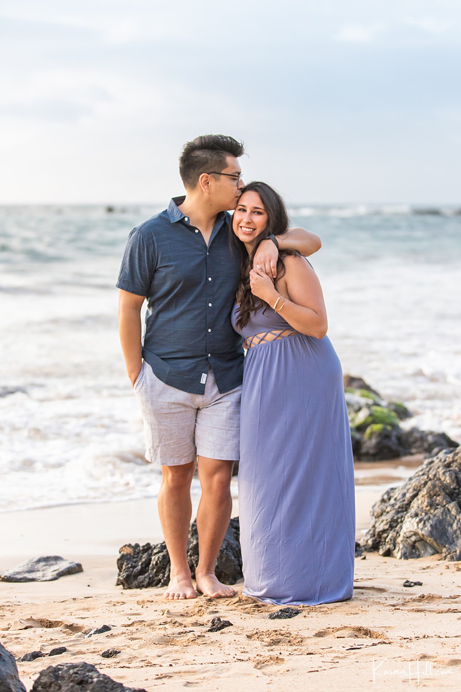 young couple embrace in front of hawaiian ocean 