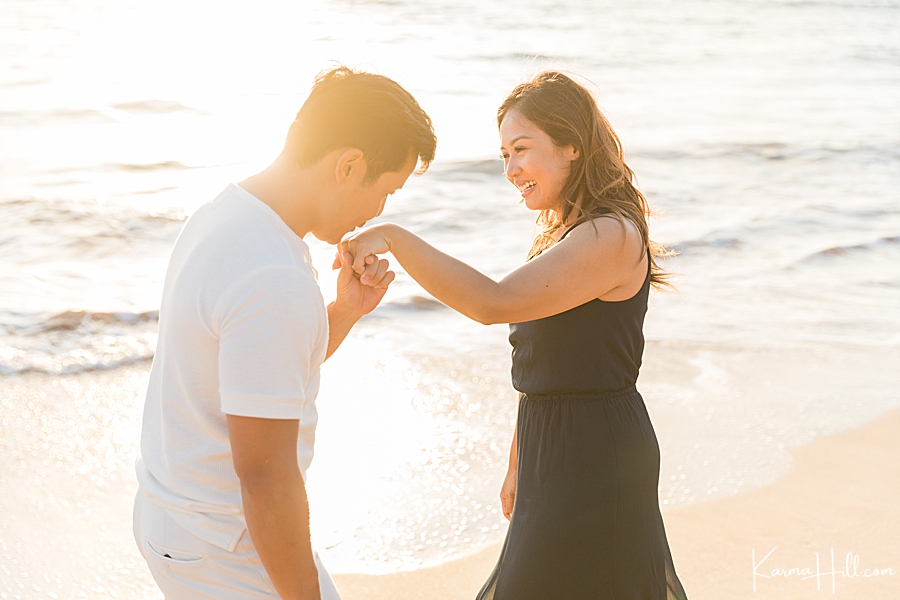 husband kisses wife's hand on a maui beach 