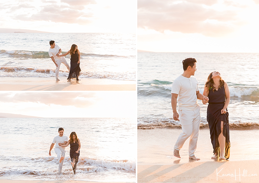husband and wife kick up ocean waves playfully at maui beach 