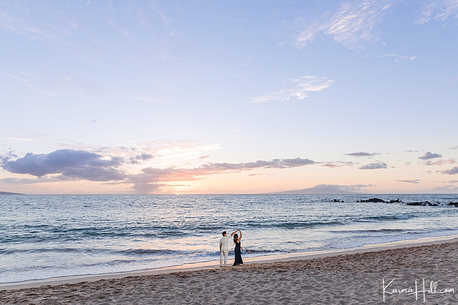 man and woman twirl and dance on hawaii beach romantically 