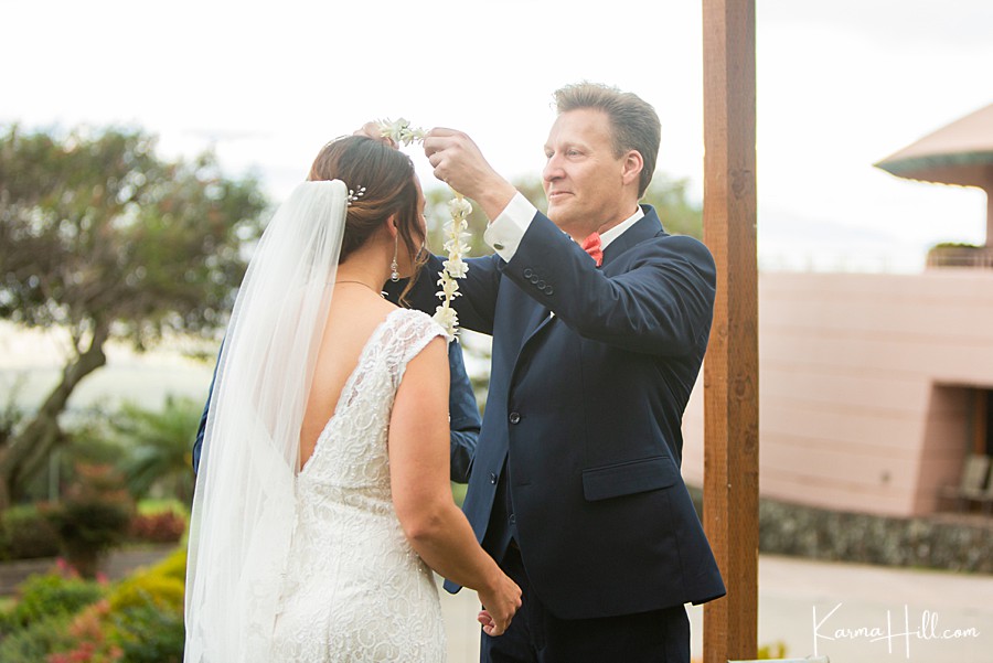 groom gives bride a white lei during their maui wedding ceremony 