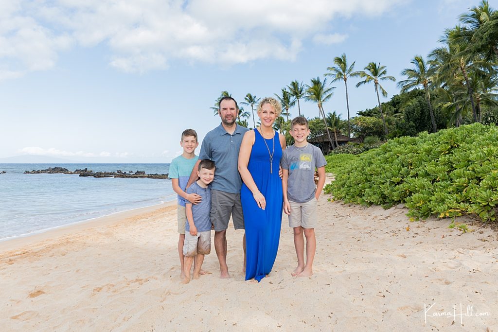 family stands together for family photos on a maui beach 