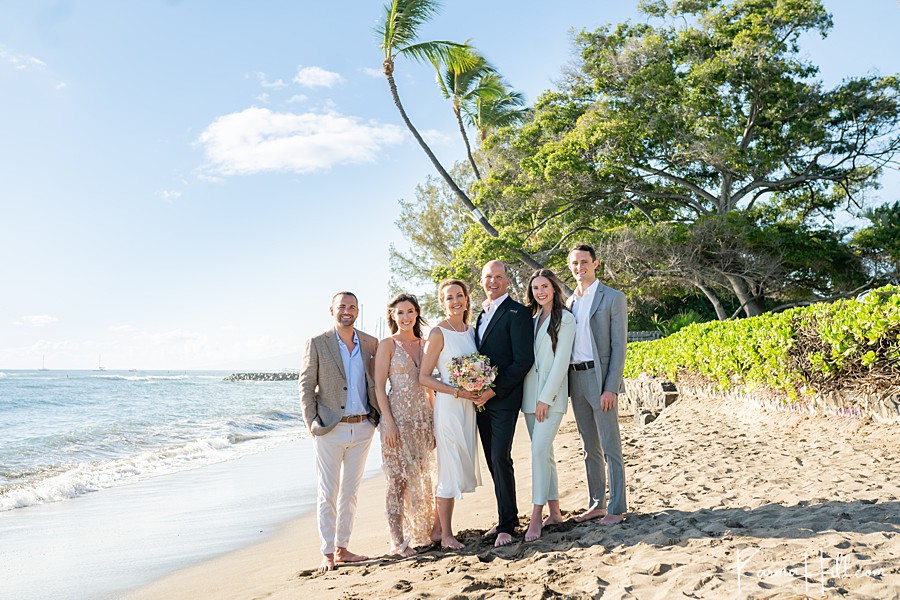 family of six adults pose on the beach during a maui beach wedding 