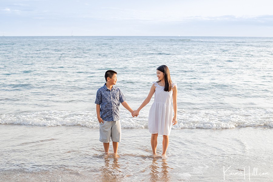 brother and sister siblings hold hands on maui beach 