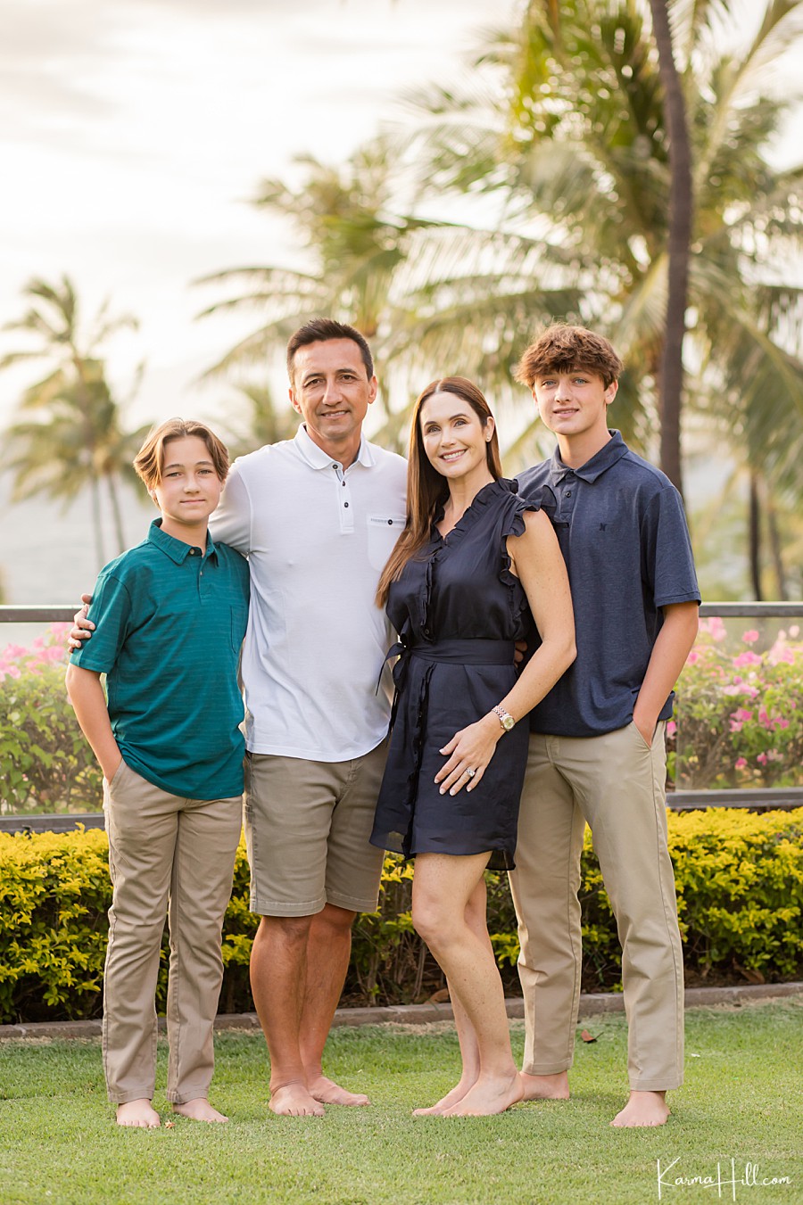 family of four poses for photos on the lawn of the four seasons in wailea 