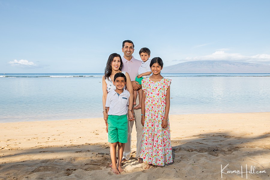 cute family poses in front of maui ocean wearing turquoise and floral prints