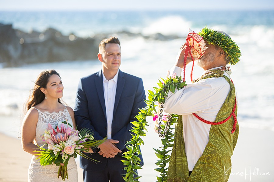 hawaiian minister blows on the conch shell to open a beach wedding in hawaii 