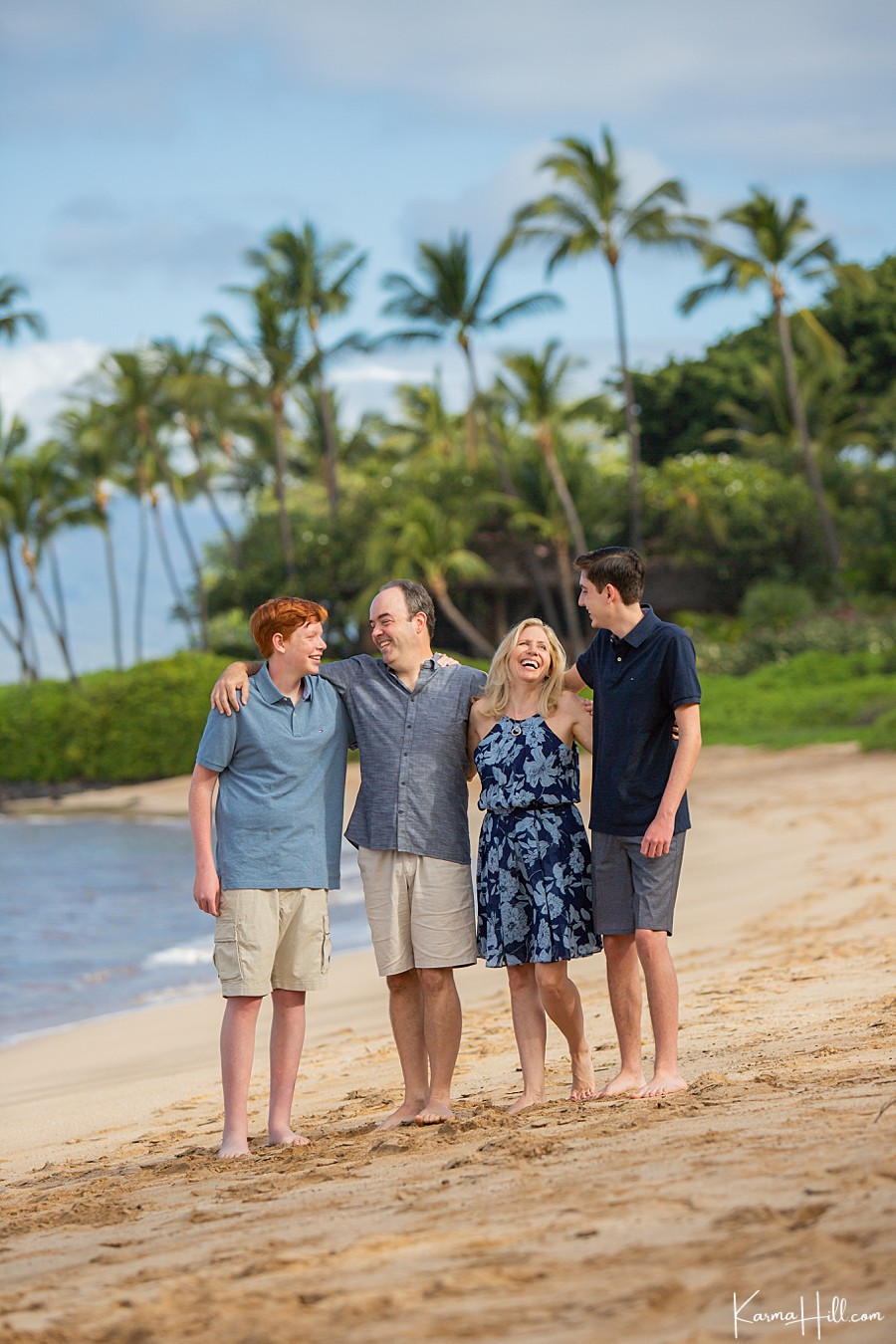 a family of four laughs together on a maui beach 