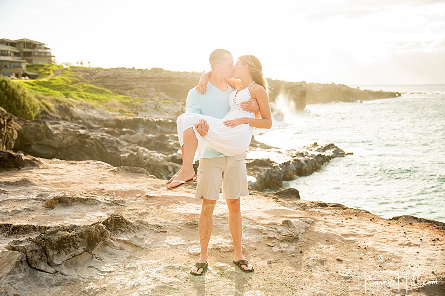 man carries woman in arms on a romantic cliffside in maui 