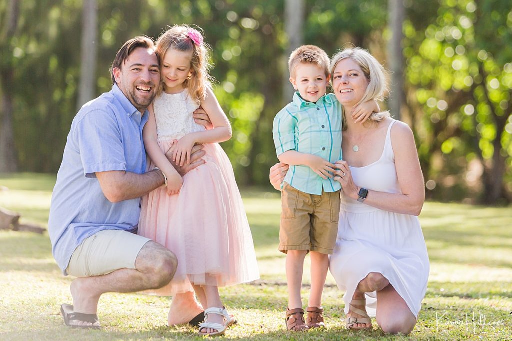 family wearing pastel colors smiles for a photo in a green park 