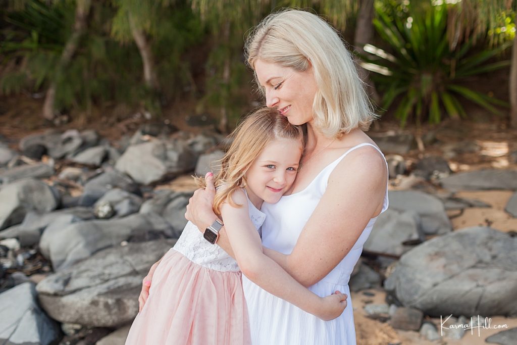 mother and daughter hug on the shore of a maui beach 