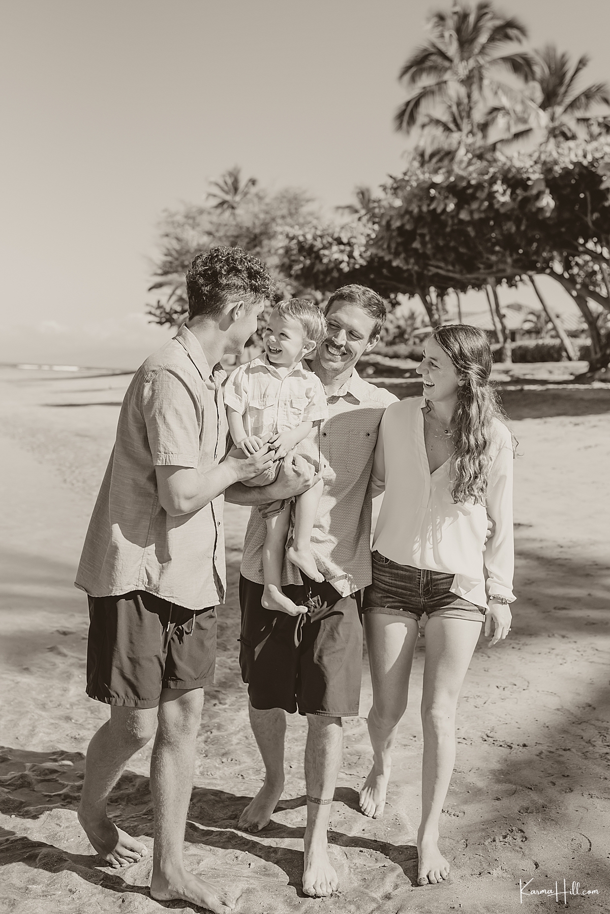 black and white image of family with young son smiling and laughing on maui beach 