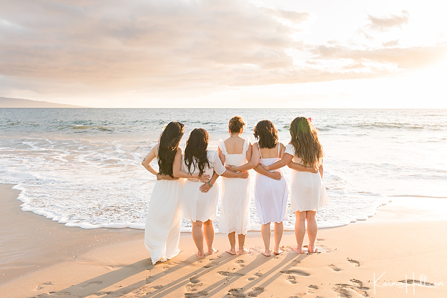 four grown daughters stand by their mother arms linked as they look into the sunset 