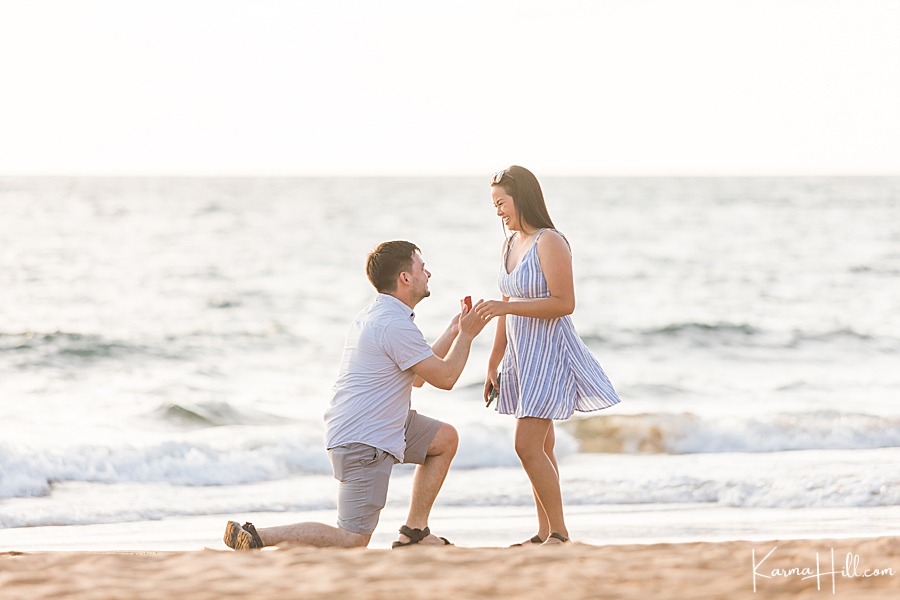 man gets down on a knee at the beach and surprises girlfriend with a ring 