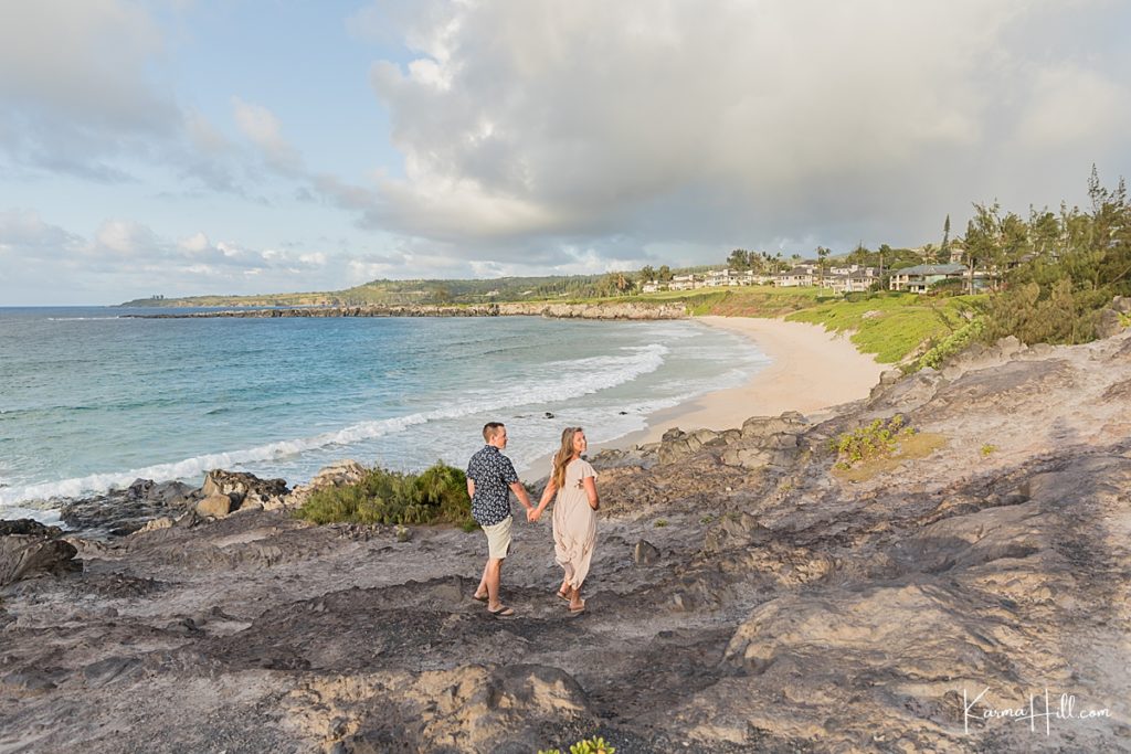 couple walks hand in hand on ironwoods beach in hawaii 