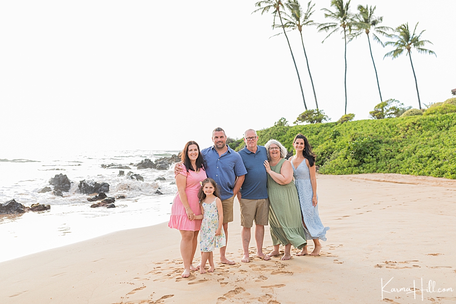 three generational family with parents and young daughter on a beach in hawaii 