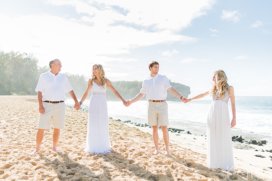 family dressed in white on kauai beach holds hands 