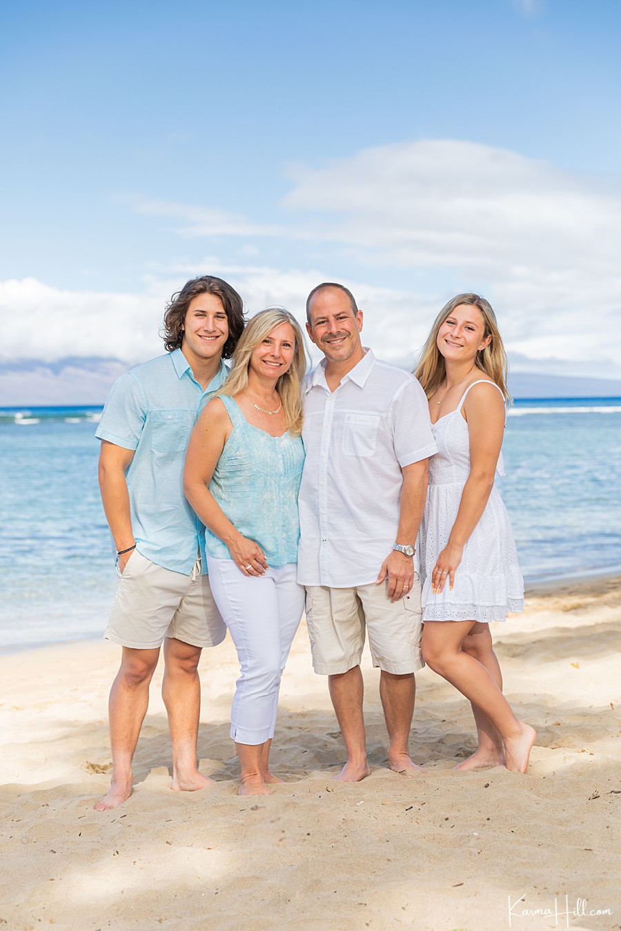 family of four poses for photo in front on the maui ocean 