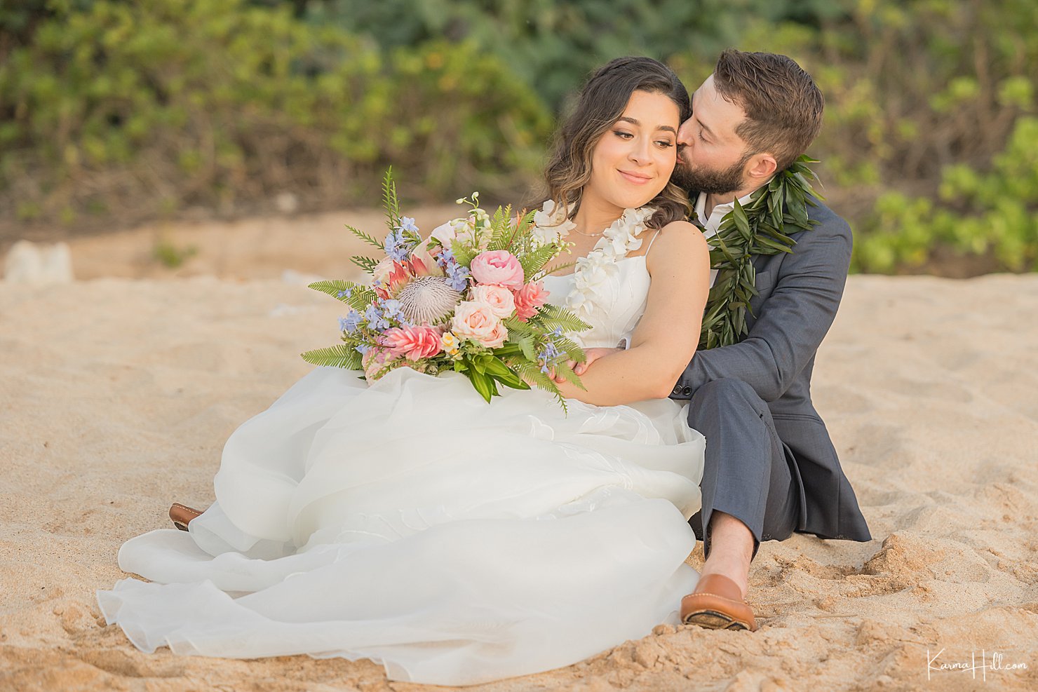 groom kissing new bride on beach